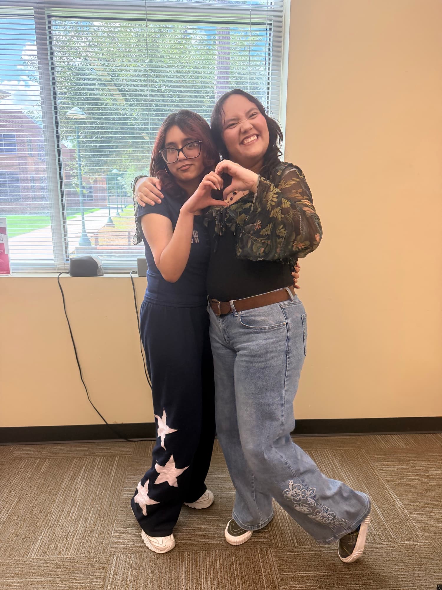 Two We Glue students making a heart shape with their hands